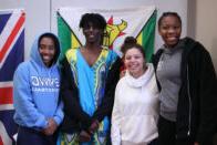 Students stand for a group photo in front of flags at an International Week event